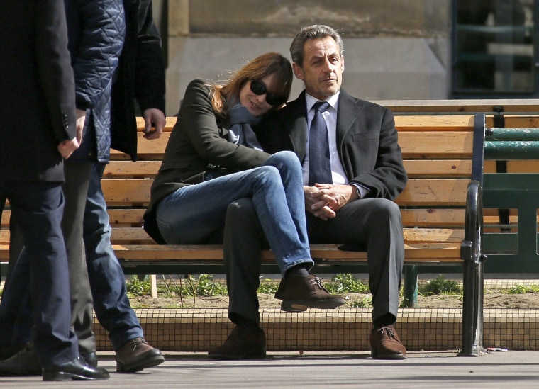Image: Former French President Nicolas Sarkozy sits on a bench with his wife and singer Carla Bruni-Sarkozy after voting at a polling station in the first round in the French mayoral elections in Paris